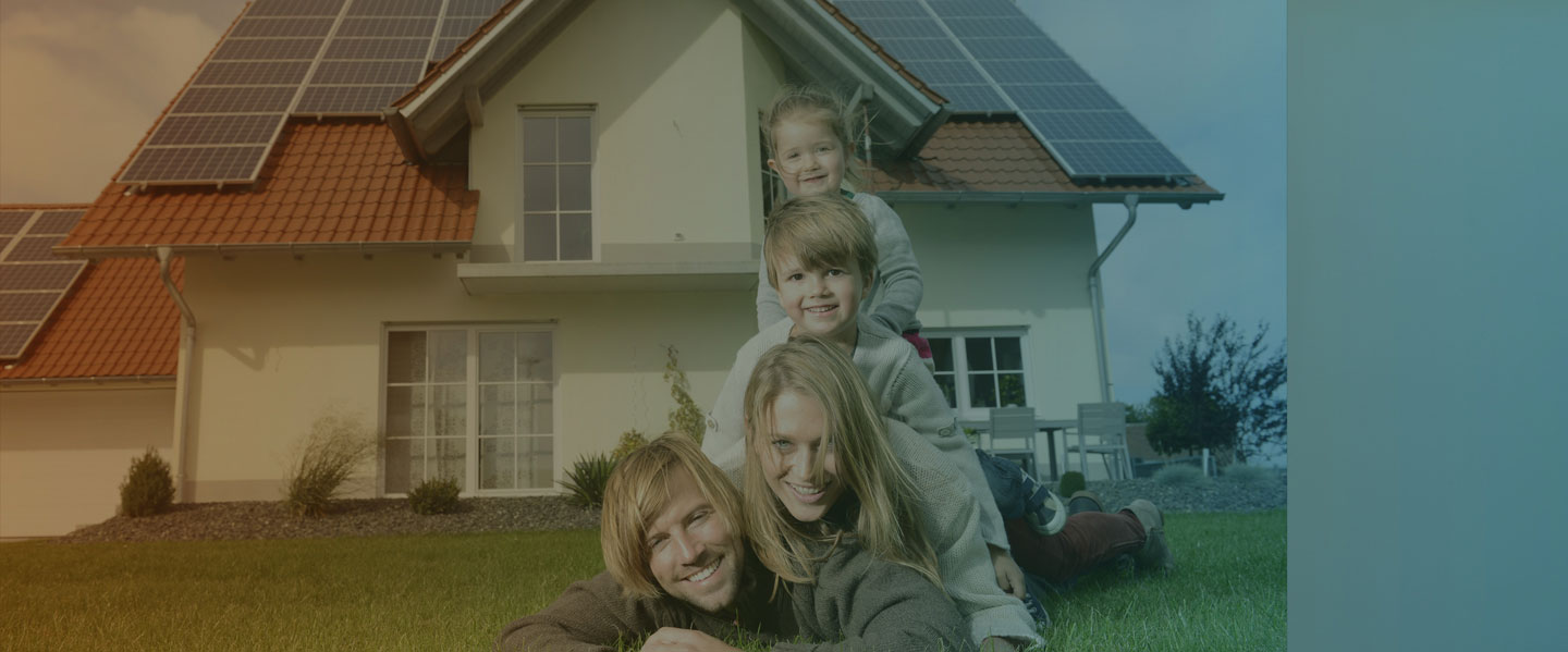 Family of 4 sitting in front of a house that has solar panels